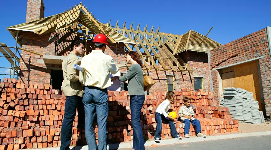 couple talking to foreman in front of house being renovated